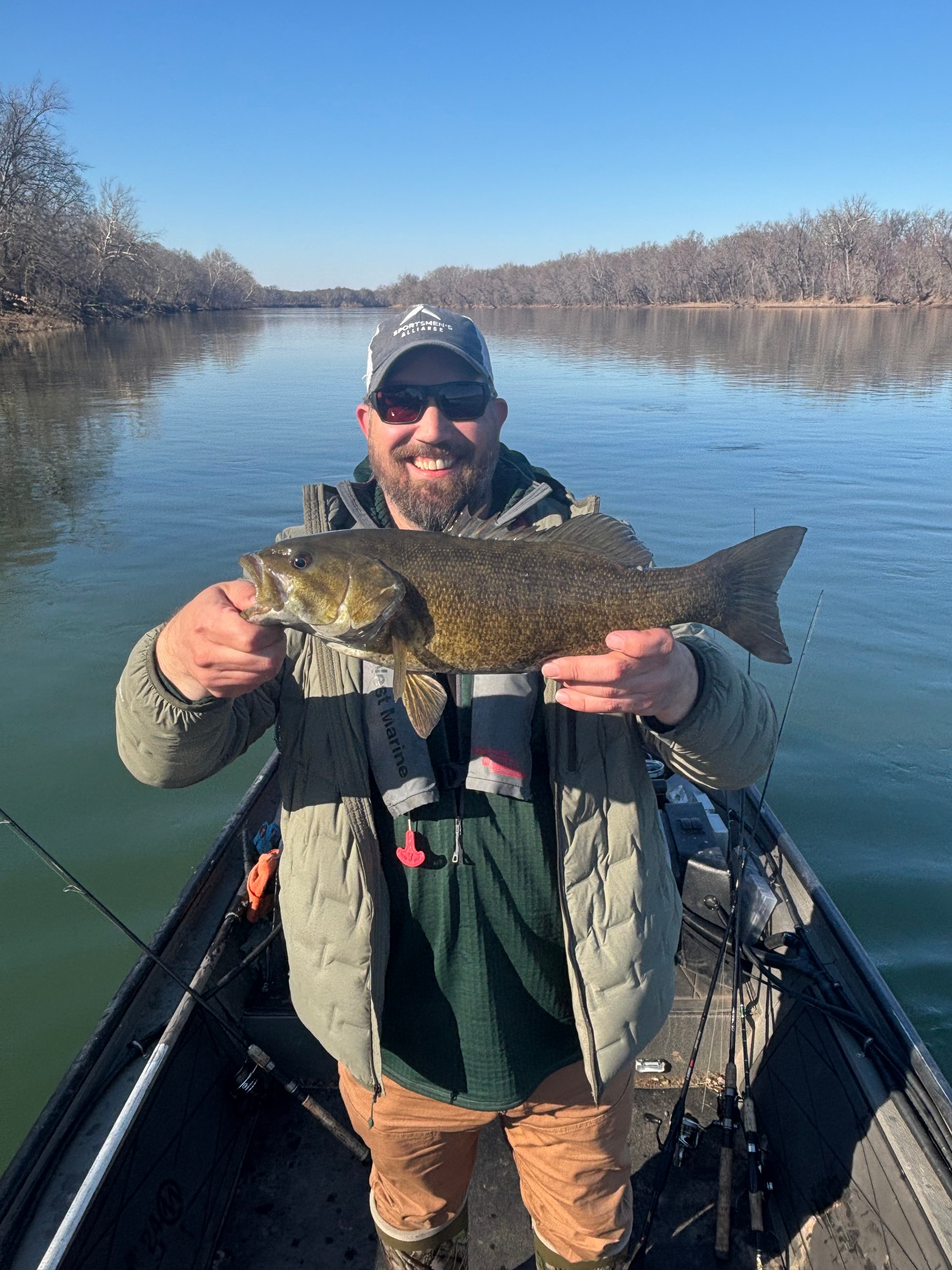 Client with a trophy smallmouth bass by a stone arch bridge
