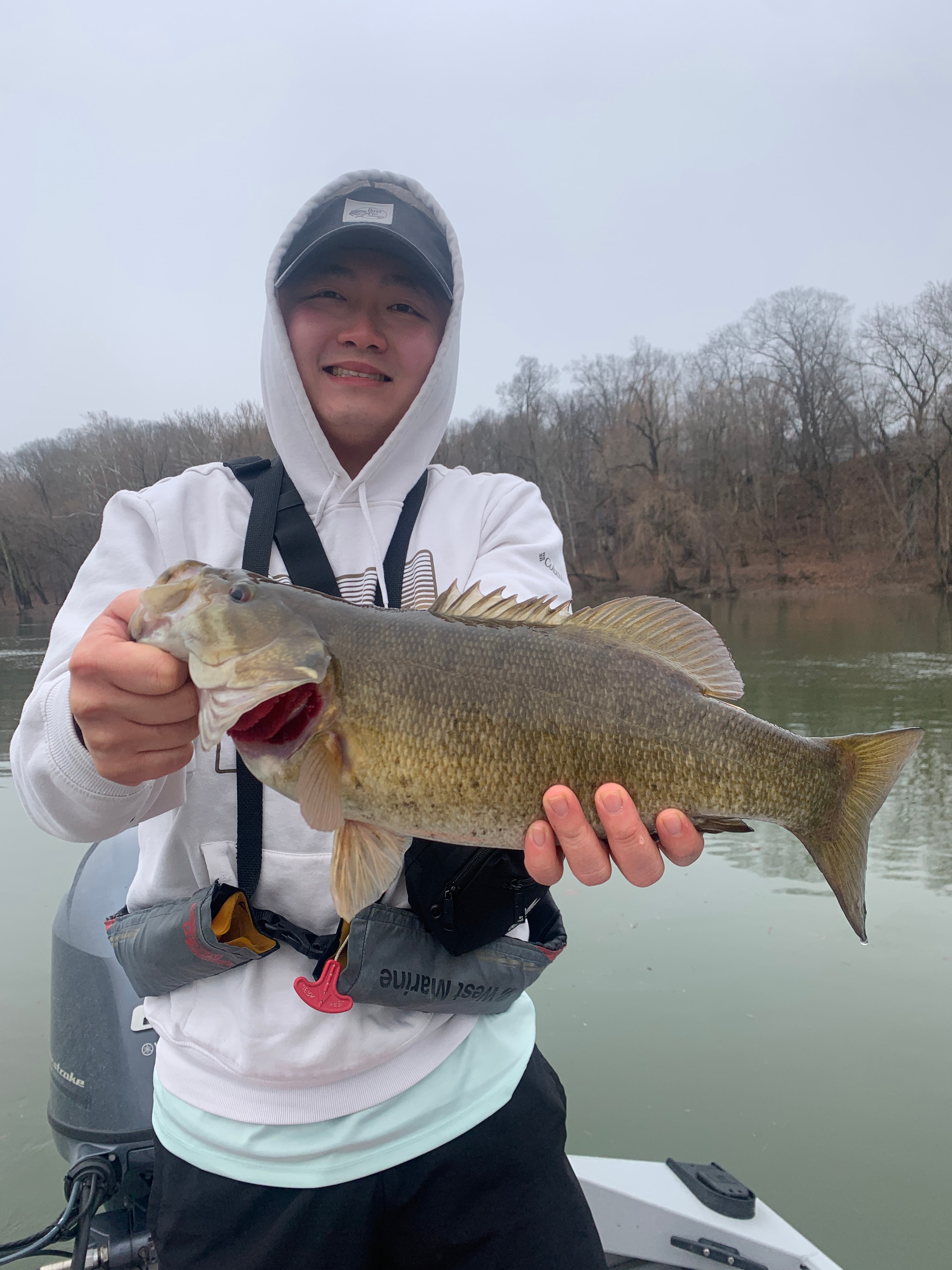 Angler holding a smallmouth bass by a stone bridge