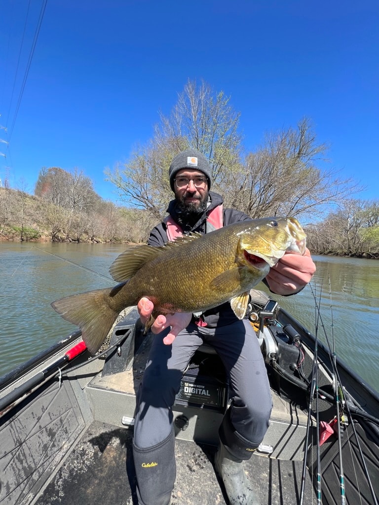 Jeff Greene holding a large smallmouth bass on the river