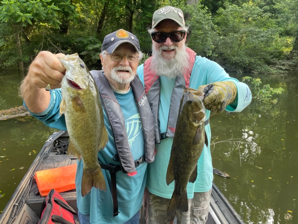 Two anglers holding smallmouth bass on guided fishing trip