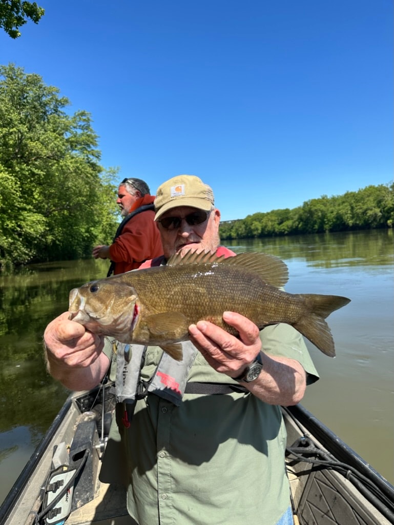 Angler holding large smallmouth bass on guided river trip